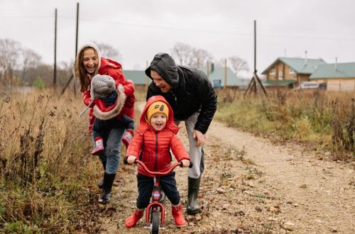 Happy family enjoying a rainy day outside with a bike ride and playful togetherness.